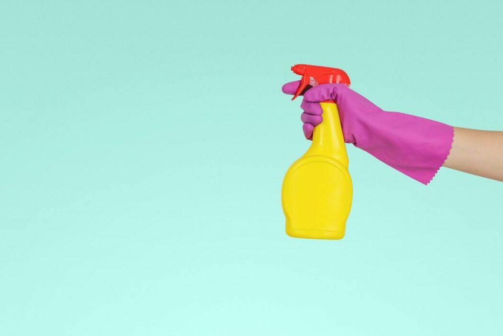 Profesionalno čiščenje stanovanja z vijoličnimi rokavicami in rumenim čistilom.