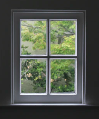 Belo PVC okno, slikano od znotraj, gleda na zeleno dvorišče.
